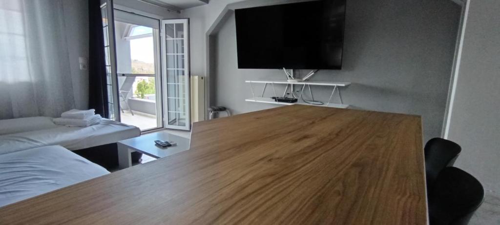 a living room with a wooden table with a tv on the wall at Αλέξανδρος 2 in Myrina