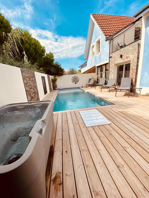 - un bain à remous sur une terrasse en bois à côté d'une maison dans l'établissement Villa balnéaire à 300m de la mer Piscine&SPA, à Châtelaillon-Plage
