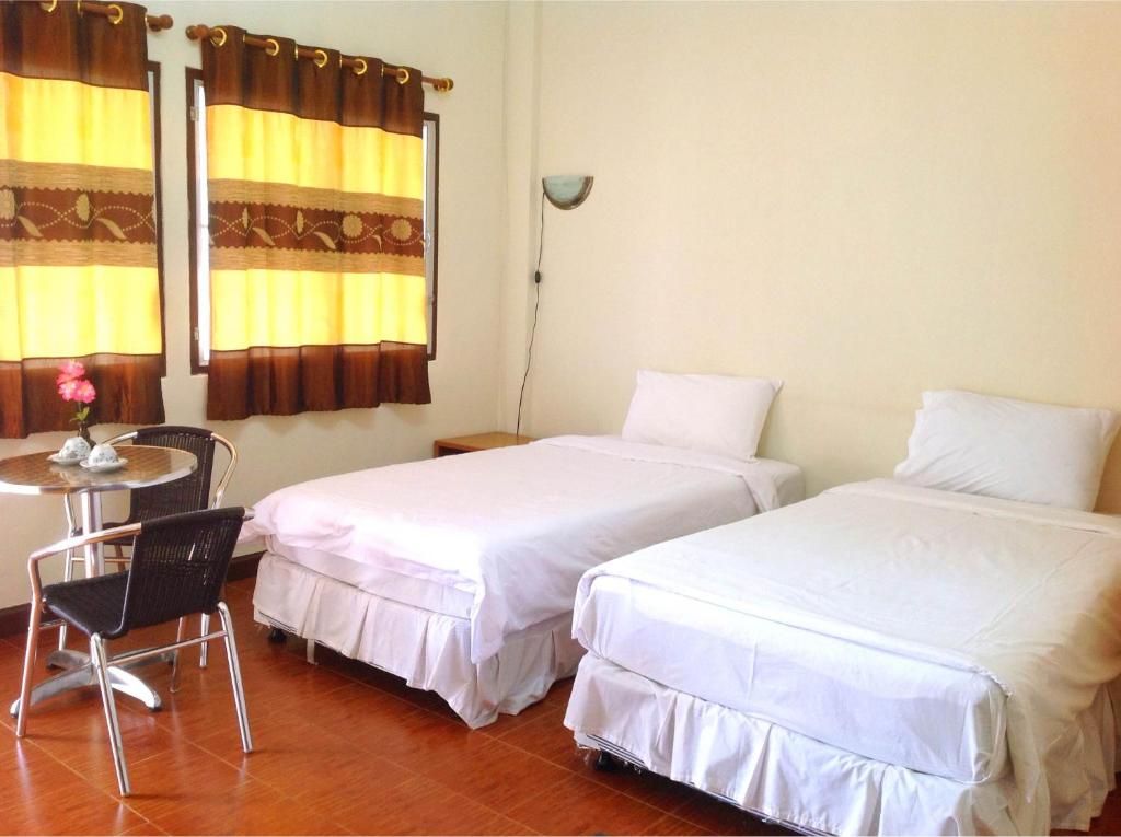 duas camas num quarto com uma mesa e uma cadeira em Sangthong Building em Mae Chaem