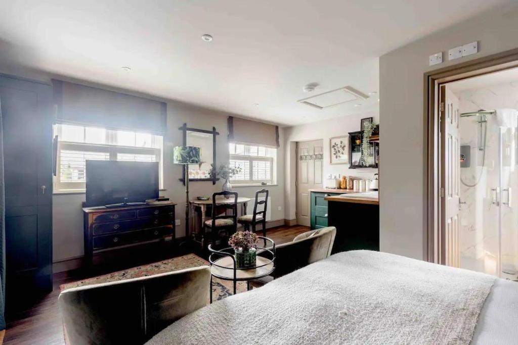a bedroom with a bed and a table and a kitchen at Stunning Private en-suite studio in Cobham in Cobham
