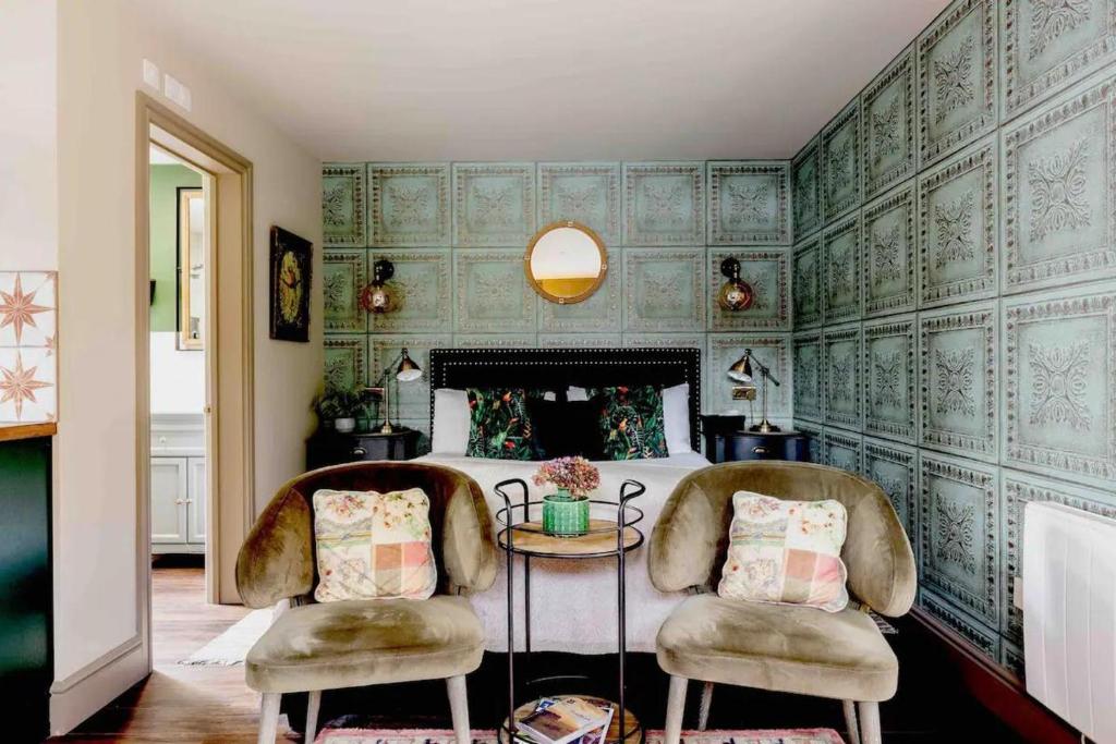 a bedroom with green wallpaper with two chairs and a bed at Stunning Private en-suite studio in Cobham in Cobham