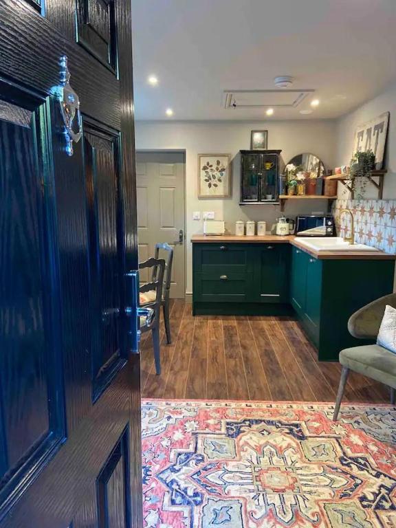 a kitchen with green cabinets and a rug on the floor at Stunning Private en-suite studio in Cobham in Cobham