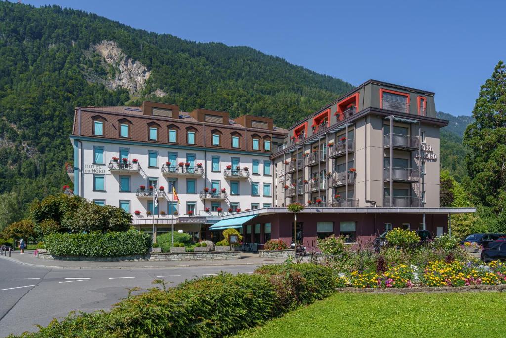 a hotel building with a mountain in the background at Hotel Du Nord in Interlaken