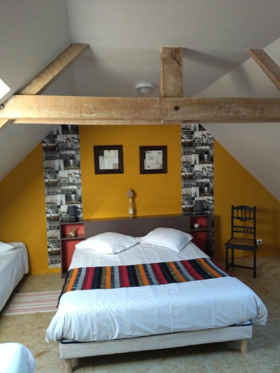 - une chambre avec un grand lit et un mur jaune dans l'établissement Grand gîte sauna et bain bouillonnant 15 pers, à Cavron-Saint-Martin