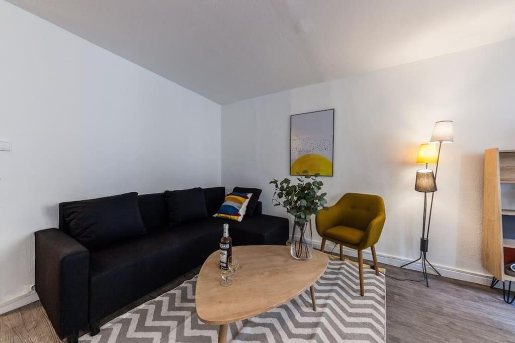 un salon avec un canapé noir et une table dans l'établissement Élégant Appartement au Panier 3EM, à Marseille
