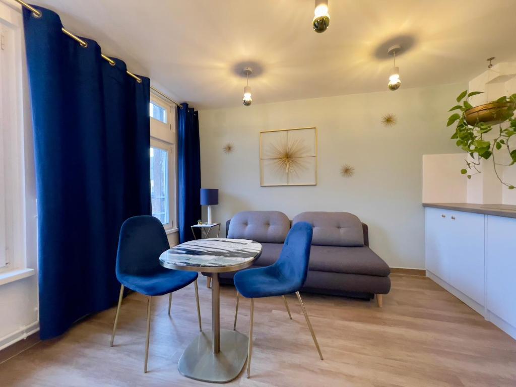 un salon avec une table et des chaises bleues dans l'établissement Appartement 2P Strasbourg centre, à Strasbourg