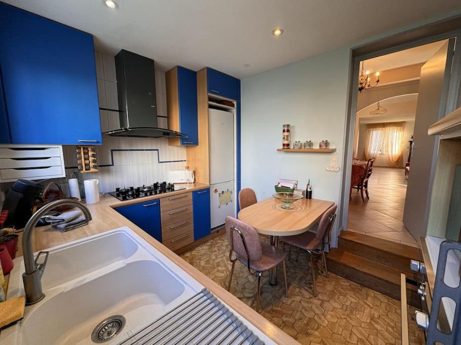 une cuisine avec une table et une cuisine avec des armoires bleues dans l'établissement Le Coquelicot - Centre - 8 Pers - Parking, au Mans
