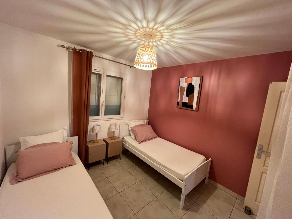 a small room with two beds and a chandelier at Villa Osao Panahy in Le Patelin