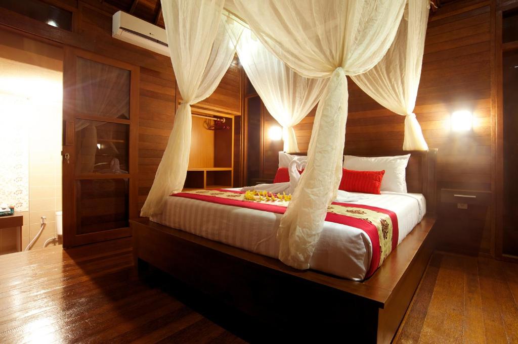 a bedroom with a canopy bed with white curtains at Saka Village Resort Ubud in Ubud