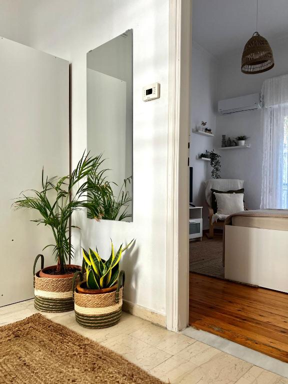 a living room with two potted plants and a mirror at Central Comfort Guesthouse in Larisa