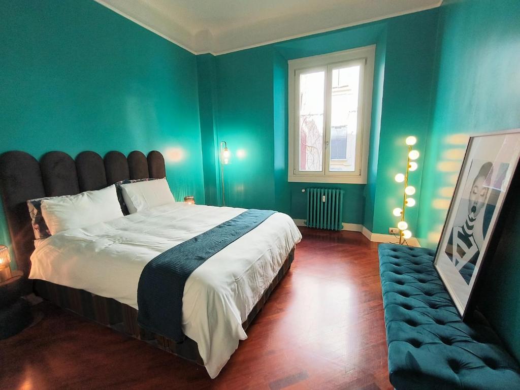 een slaapkamer met een bed met groene muren en een raam bij CityLife & Fiera Milano Apartment with AC, WiFi, Metro M1 and Airport link in Milaan