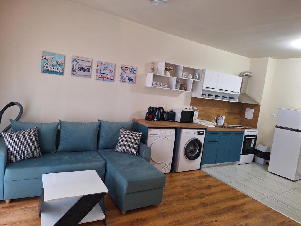 a living room with a blue couch and a kitchen at Studio Anelia in Sveti Vlas
