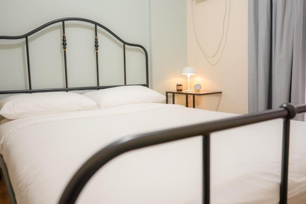 een slaapkamer met een wit bed met een metalen frame bij Alea Residences in Manilla