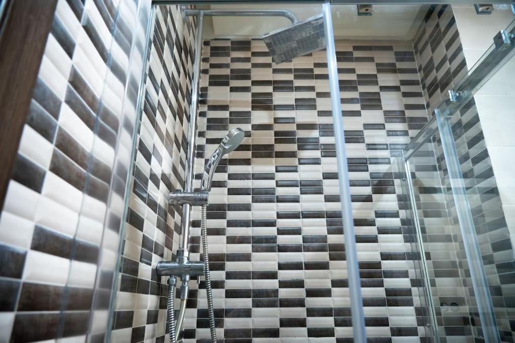 eine Dusche im Bad mit einer gefliesten Wand in der Unterkunft Prime 2BR Agadir Apt with Pool, Near Beach and Cafés in Agadir