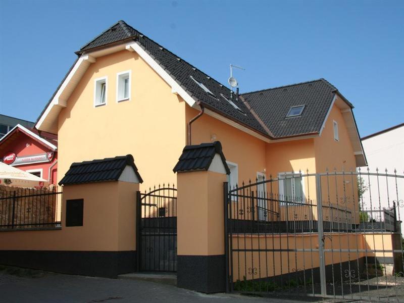 una casa amarilla y naranja con una valla negra en Villa Amenity, en Světlá nad Sázavou