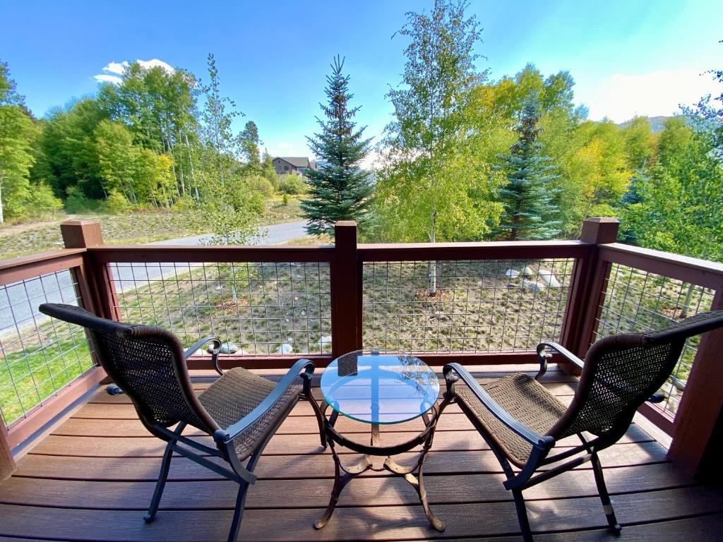 un patio avec deux chaises et une table en verre sur une terrasse dans l'établissement Frey Gulch 58 by SummitCove Lodging, à Keystone