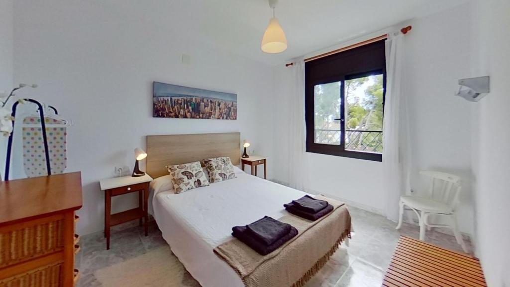 a bedroom with a bed and a desk and a window at Villa Mirador del Mar hostel in Comarruga