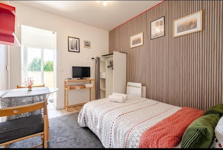 a bedroom with a bed and a desk and a television at Studio 1pièce cosy Paris-Disney in Vaires-sur-Marne
