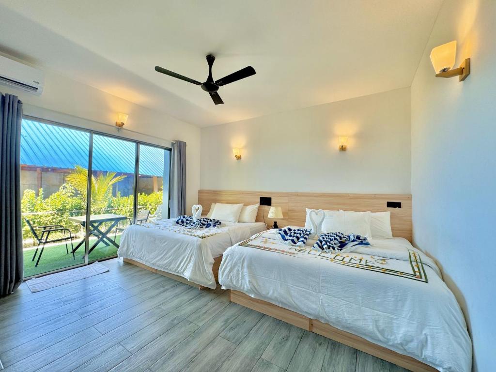 a bedroom with two beds and a ceiling fan at La Solara Villa in Ukulhas