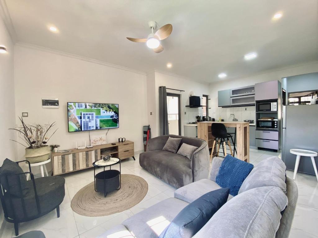 a living room with a couch and a tv at Sunset Views 3-Bedroom Apt, 1min Walk to Beach - NYHA1 in Flic-en-Flac