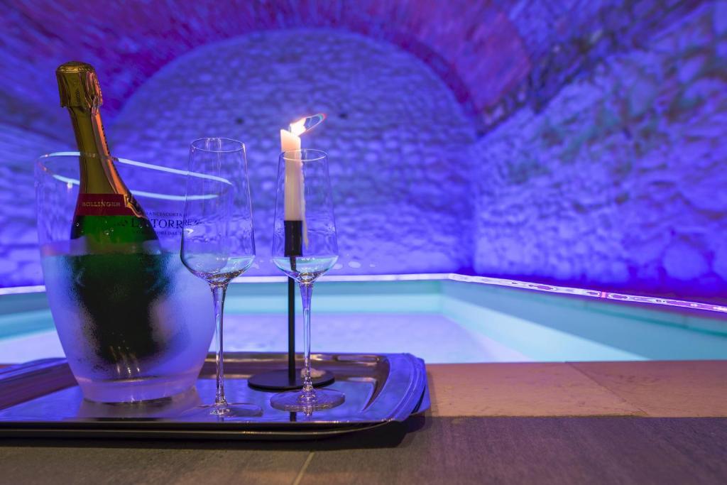 una bottiglia di vino e bicchieri su un vassoio accanto alla piscina di Locanda al Vescovo a Verona
