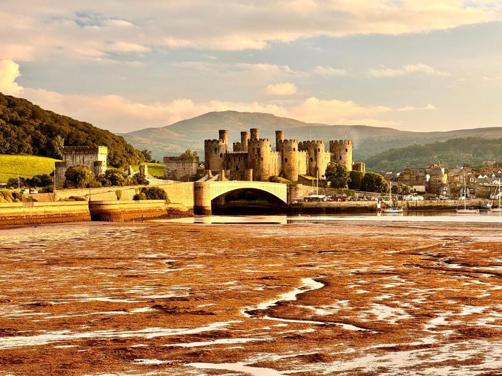 a large castle with a bridge and a city at Llandudno Boutique style seaside retreat with stunning views in Llandrillo-yn-Rhôs