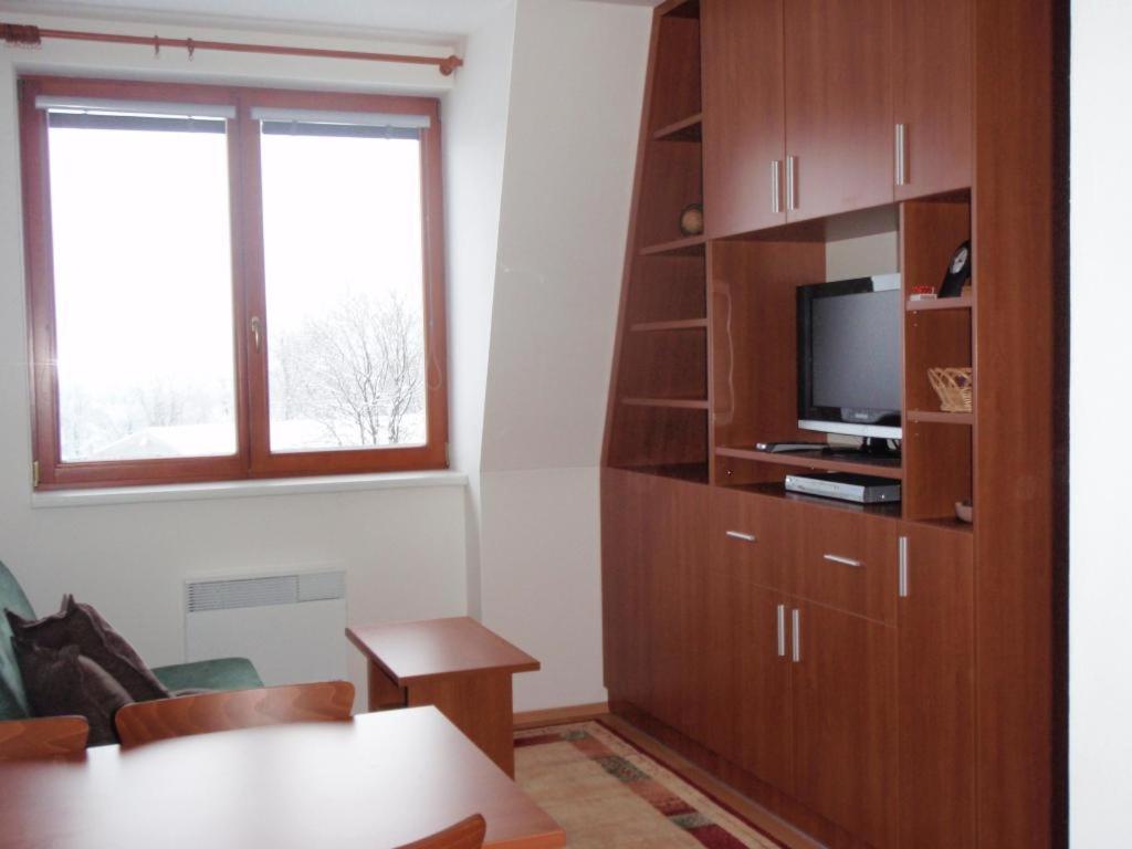 a living room with a tv and a wooden book shelf at Apartmán Ramzová B14 in Ramzová