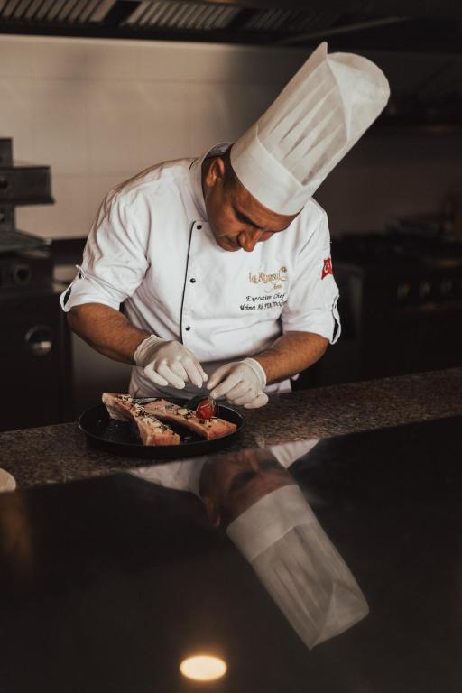 a chef preparing food on a plate in a kitchen at La Kumsal Hotel in Kaş