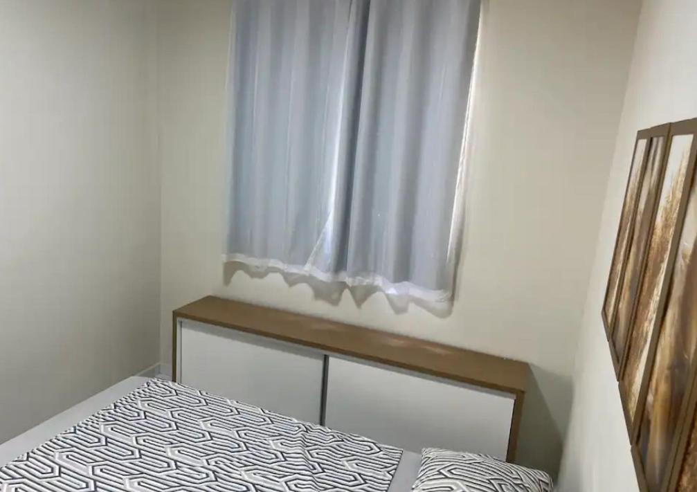 una camera da letto con un letto e una finestra con una tenda di Apartamento 108 a Caruaru