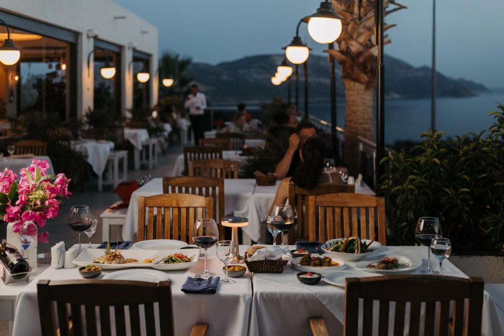 a restaurant with tables with plates of food and wine glasses at La Kumsal Hotel in Kaş