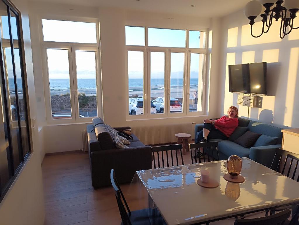 une personne assise sur un canapé dans un salon dans l'établissement Sable d'Opale, à Le Portel