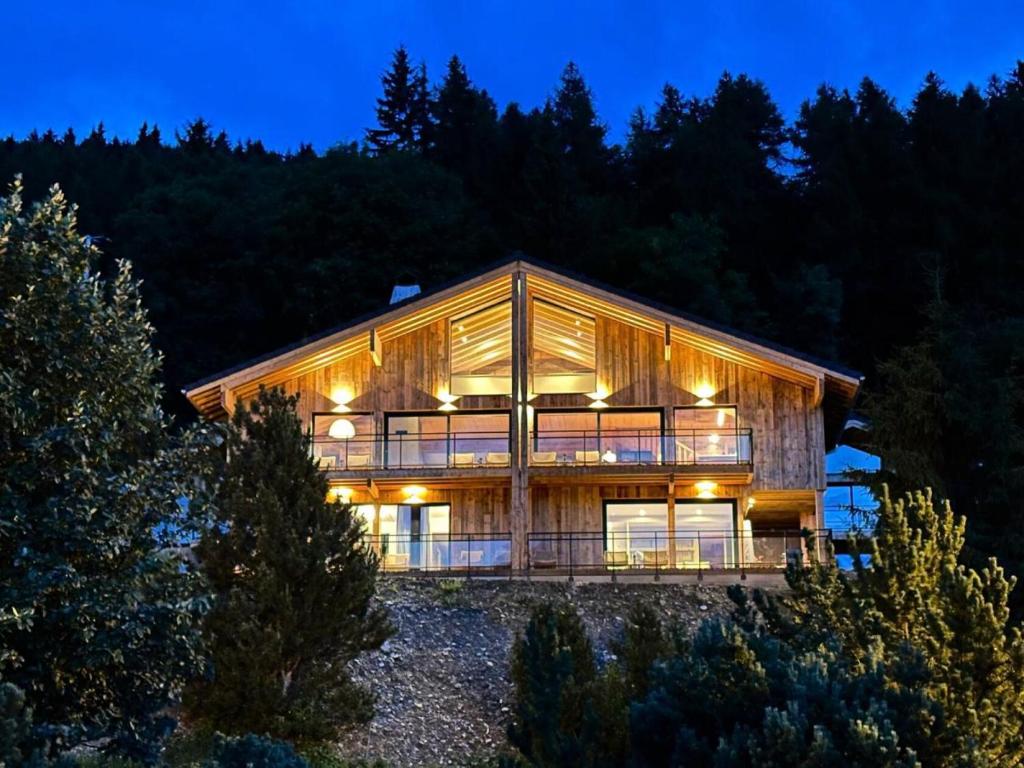 ein großes Holzhaus in der Nacht mit Bäumen in der Unterkunft Chalets De La Grande Ourse - Sublime Chalet 16 personnes avec sauna & Jacuzzi ! MAE-8951 in La Plagne Tarentaise