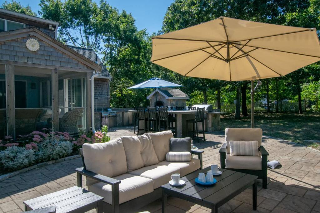 un patio con sofá y sombrilla en Outdoor entertaining re-imagined Enjoy a new luxury back yard, en Eastham