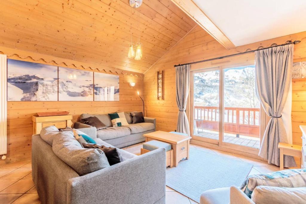 un salon avec deux canapés et une grande fenêtre dans l'établissement Les Chalets Du Gypse - LES CHALETS DU GYPSE C10 MAE-3651, à Saint-Martin-de-Belleville