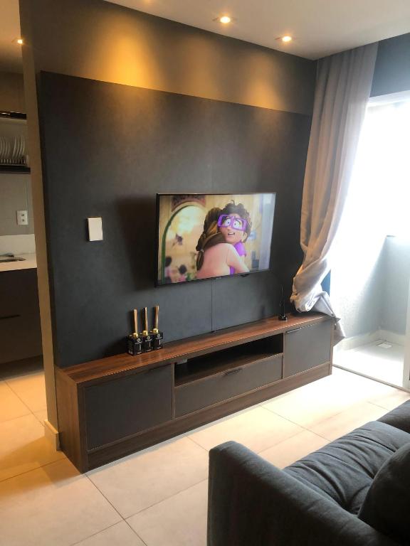 a living room with a flat screen tv on a wall at Flat Red Sorocaba - Gray in Sorocaba
