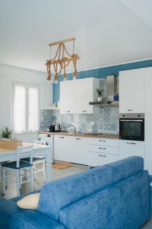 a living room with a blue couch and a kitchen at Casa degli Ulivi - Apartment B in Porto San Giorgio