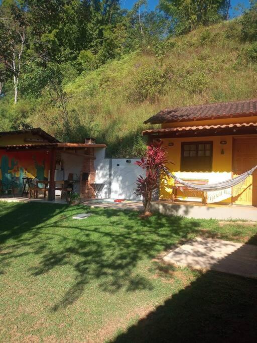 a small yellow house with a hill behind it at Chalé no Sana - Equilíbrio e Descanso in Sana