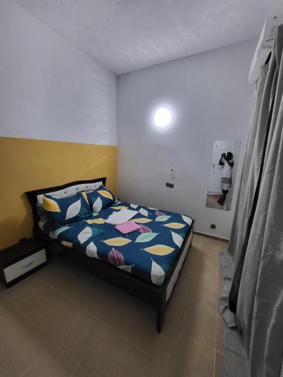 ein Schlafzimmer mit einem Bett mit einer bunten Bettdecke in der Unterkunft Résidence Bon Séjour in Abidjan