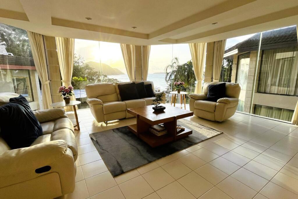 a living room with couches and a table and a large window at 3BR Condo in Rawai, Phuket with Exclusive Beach in Ban Saiyuan (1)