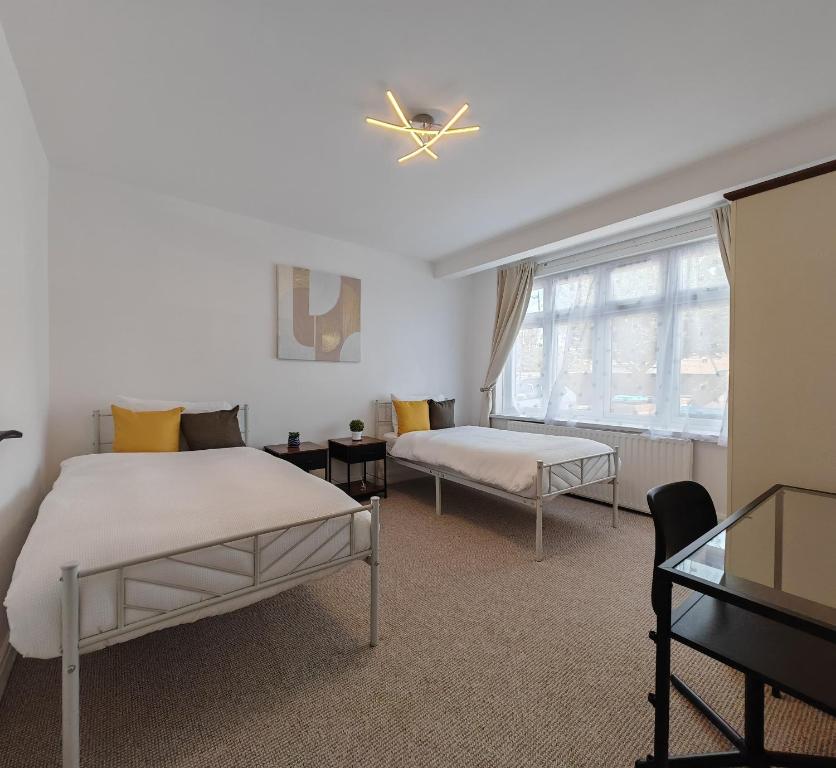 a bedroom with two beds and a window at 4 Bedroom 2 Bathroom House - Free parking in Ponders End