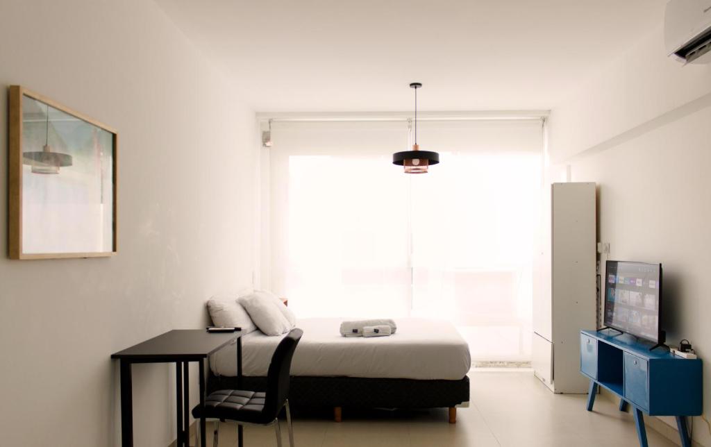 Un dormitorio con una cama y un escritorio y una ventana. en Amplio monoambiente con piscina, en Buenos Aires