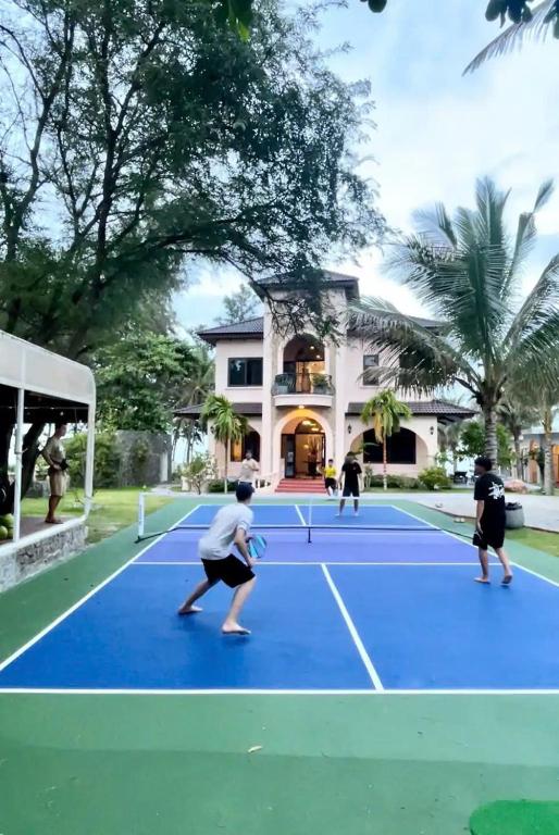 three people playing tennis on a tennis court at Villa C62 - Private Swimming Pool 100M2 - In Stunning Sea Front Location in Mui Ne
