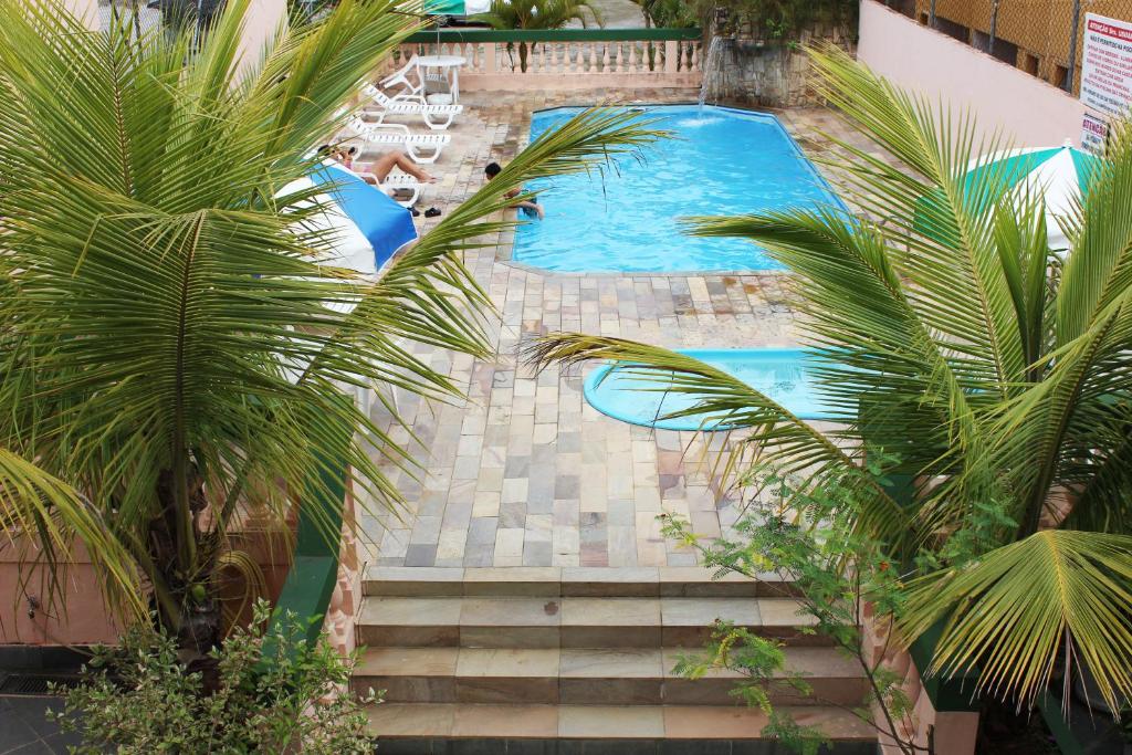 uma vista sobre uma piscina com palmeiras em Farol das Gaivotas Pousada e Residence em Caraguatatuba