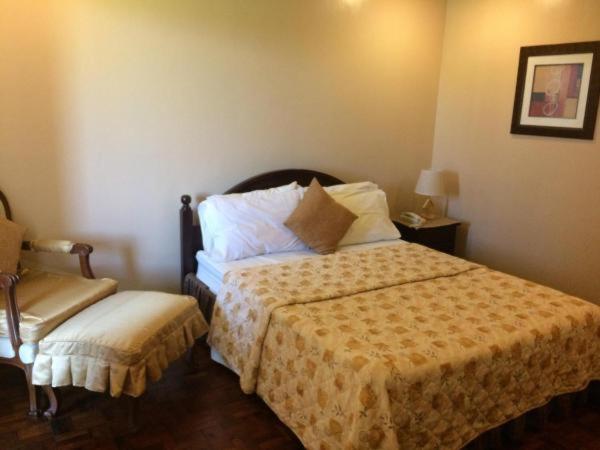 a hotel room with a bed and a chair at Casa Cecilia Heritage Hotel in Taal