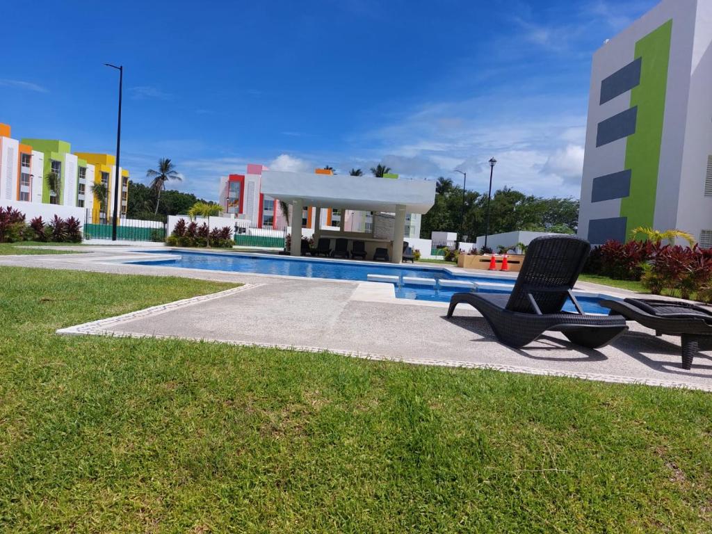 einem Pool mit zwei Stühlen vor einem Gebäude in der Unterkunft Hermoso departamento con alberca in La Sabana