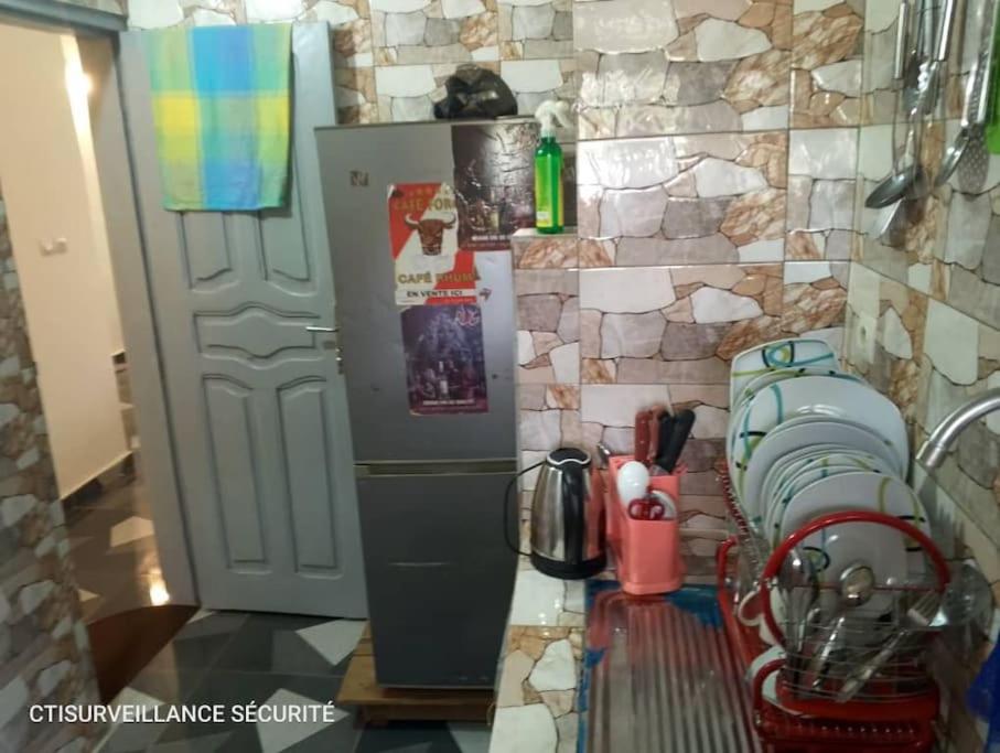 cocina con nevera y pared de piedra en Résidence Meublée Smart 2, en Man