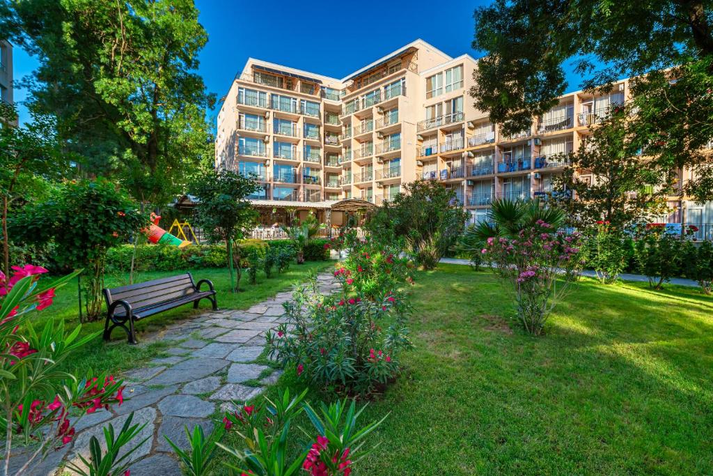 a park with a bench in front of a building at Hotel Riva Park - All Inclusive in Sunny Beach