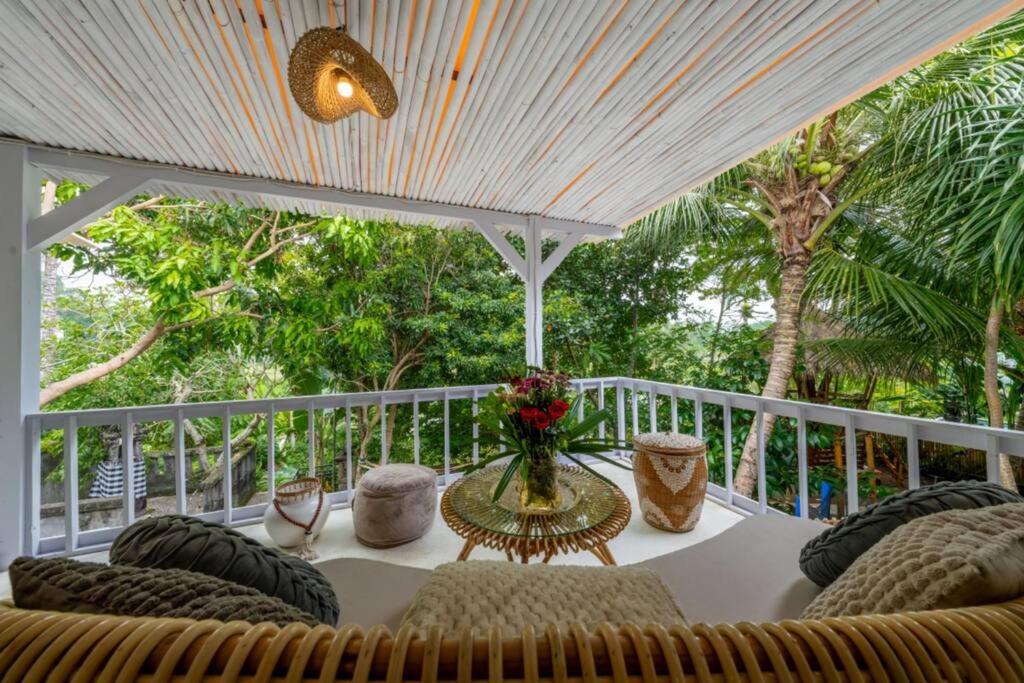 a table with chairs and a vase of flowers on a porch at Family Villa Ubud, 2 bedrooms, Shared Pool, Garden, Rice Field & Jungle Views in Ubud