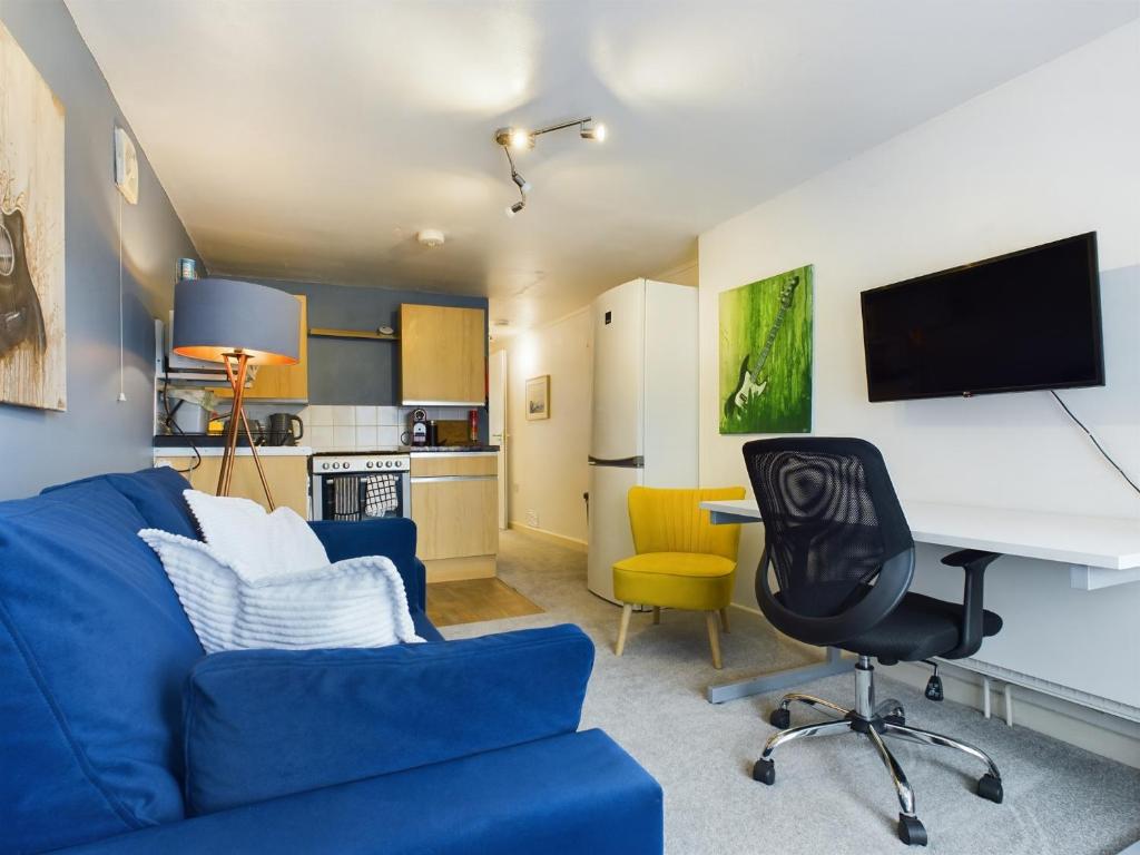 TilehurstにあるLovely 1 bedroom apartment with parkingのリビングルーム(青いソファ、デスク付)