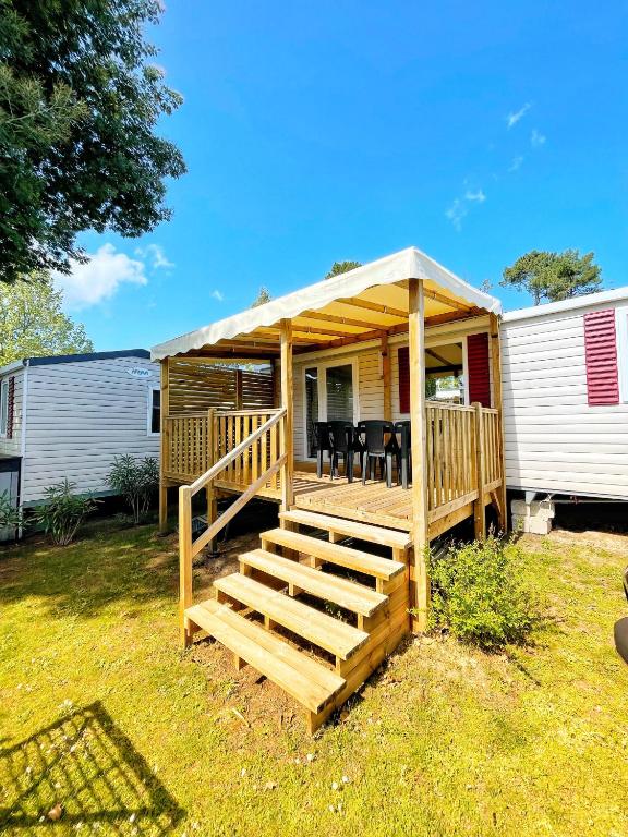 une maison avec une terrasse avec une table et des chaises dans l'établissement Mobilhome au CAP FERRET - Camping 4 étoiles, à Lège-Cap-Ferret